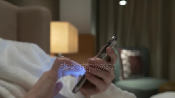 젊은 여자의 손 전화 사진 스크롤 입력 sms. 여성의 손을 침대에 저녁에는 스마트폰을 사용합니다. 4 k — 비디오