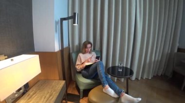 Akşamları, kadın oturma odasında rahat bir koltuğa oturur onun smartphone--dan video görüşmeler ve notları bir defterde yapar. 4k