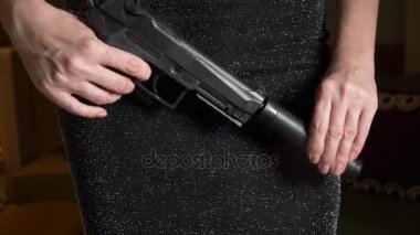 Silahlı bir kadın bir susturucu ve sinyal bozucu bir cıvata üzerinde koyarak onun elinde bir silah tutar. yakın çekim, 4k. Ağır çekim