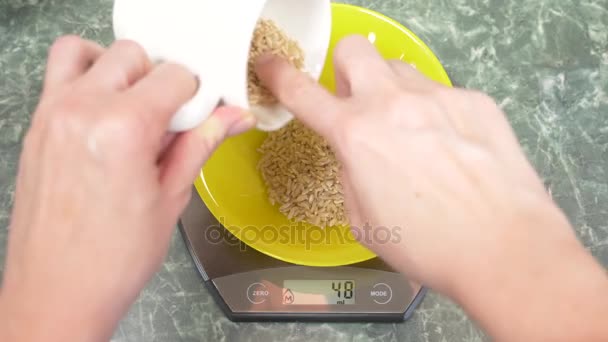 Someone measures brown rice electronically in the kitchen. 4k, — Stock Video