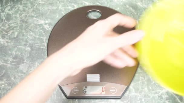 Mains féminines mettre un plat jaune sur une balance électronique de cuisine. 4k . — Video