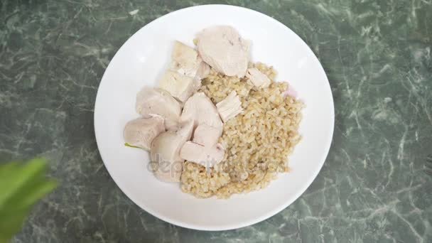 Las manos femeninas ponen las hojas de ensalada en un plato de servir con arroz integral y pechuga de pollo hervida. 4k — Vídeos de Stock