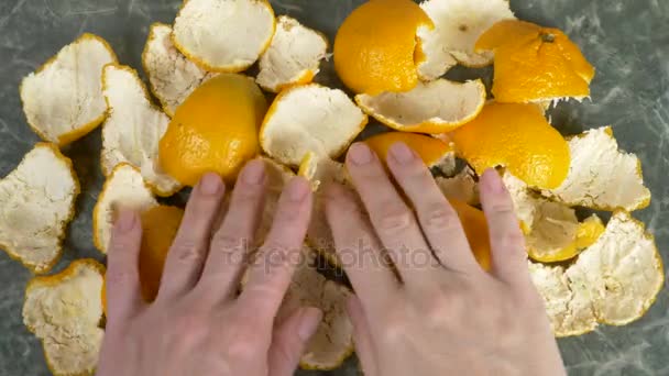 Женские руки снимают кожуру мандарина со стола. 4к, замедленная съемка, копировальное пространство — стоковое видео