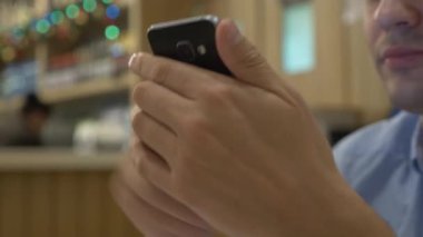 Bir smartphone kullanarak, kahve içme ve bir kafede dinlenirken gülümseyen yakışıklı genç adam. Noel zamanı. 4k