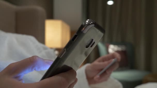 Achetez en ligne avec votre smartphone et votre carte de crédit. Les mains féminines utilisent la carte et le téléphone le soir dans l'appartement. 4k — Video