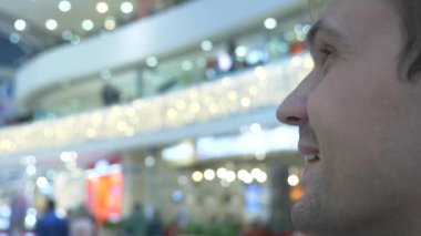 yakın çekim profil modern bir alışveriş merkezi insanlarda bakar bir adam. Arka plan bulanık. 4k