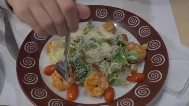 Uma rapariga no café a comer salada Caesar com camarões. 4k — Vídeo de Stock