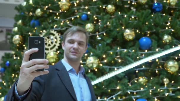 Człowiek robi selfie na telefon na choince w nowoczesne centrum handlowe. Niewyraźne tło. 4k — Wideo stockowe