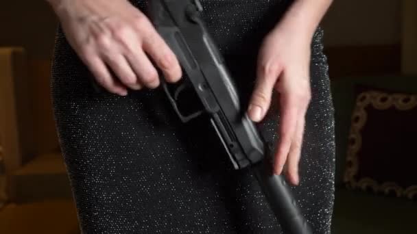 Вооруженная женщина держит в руках пистолет, надевая глушитель и глушитель. Крупный план, 4К. Медленное движение — стоковое видео