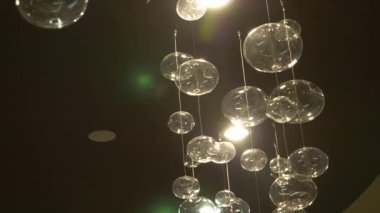 lambaları yakın çekim. Kristal modern avize ayrıntılı arka plan. Kabarcıklar şeklinde lambaları yanıp sönen yansıma parlayan bir asılı. Ağır çekim. 4k