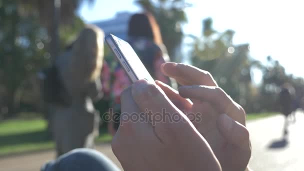 Primer plano de un hombre usando un teléfono inteligente móvil, al aire libre. Primer plano de un hombre de las manos mensajes de texto en su teléfono inteligente en las calles de la ciudad durante el día soleado. 4k, cámara lenta — Vídeo de stock