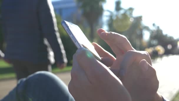 Primer plano de un hombre usando un teléfono inteligente móvil, al aire libre. Primer plano de un hombre de las manos mensajes de texto en su teléfono inteligente en las calles de la ciudad durante el día soleado. 4k, cámara lenta — Vídeo de stock