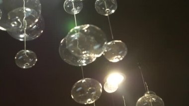 lambaları yakın çekim. Kristal modern avize ayrıntılı arka plan. Kabarcıklar şeklinde lambaları yanıp sönen yansıma parlayan bir asılı. Ağır çekim. 4k