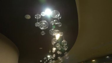 lambaları yakın çekim. Kristal modern avize ayrıntılı arka plan. Kabarcıklar şeklinde lambaları yanıp sönen yansıma parlayan bir asılı. Ağır çekim. 4k