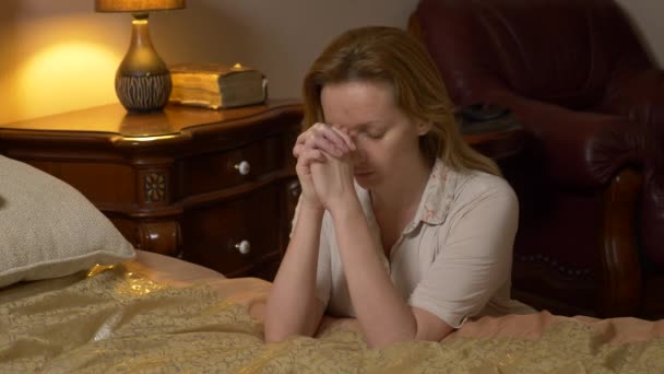 Eine junge blonde Frau betet, bevor sie zu Bett geht. 4k — Stockvideo