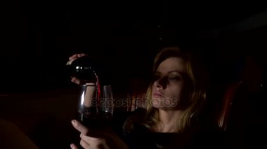 Üzgün, güzel bir kadın geceleri şarap içme. yakın çekim, 4k, ağır çekim.