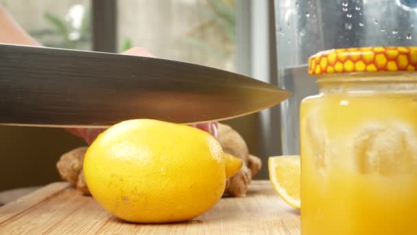 Female hands cut a knife with lemon for a drink made from citrus handmade with ginger root. 4k — Stock Video