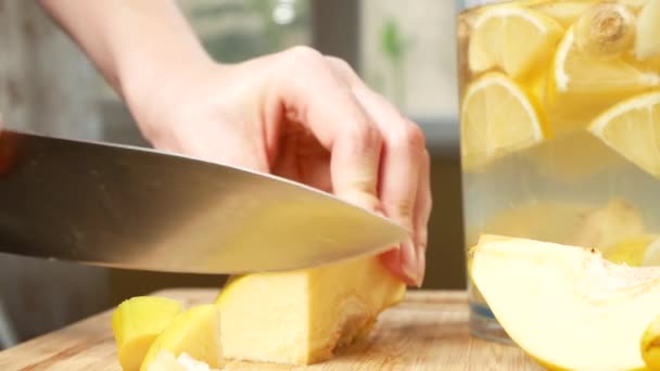 Mãos de mulheres cortadas em pedaços de marmelo para uma bebida feita de citrinos feitos à mão com gengibre. 4k , — Vídeo de Stock