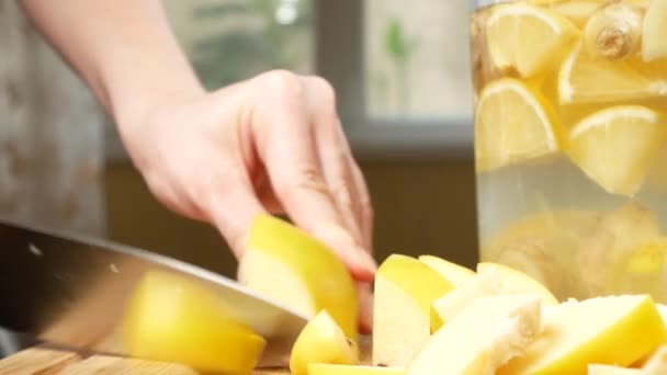 Mãos de mulheres cortadas em pedaços de marmelo para uma bebida feita de citrinos feitos à mão com gengibre. 4k , — Vídeo de Stock