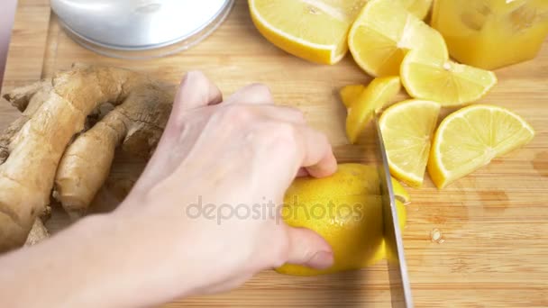 Frauenhände schneiden ein Messer mit Zitrone für ein Getränk aus Zitrusfrüchten, handgemacht mit Ingwerwurzel. 4k, Zeitlupe — Stockvideo