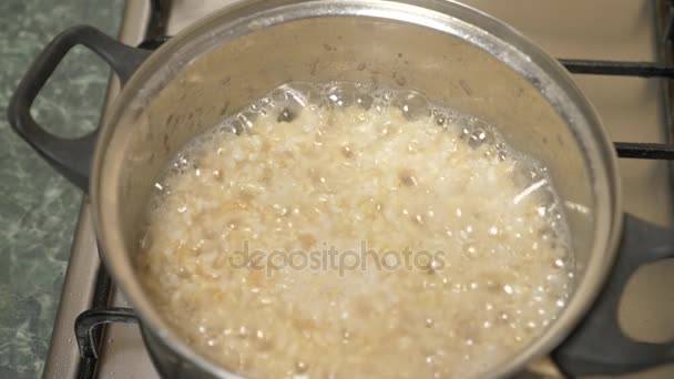 Preparação de arroz integral. Água fervente com cereais em uma panela no fogão. 4k, câmera lenta — Vídeo de Stock