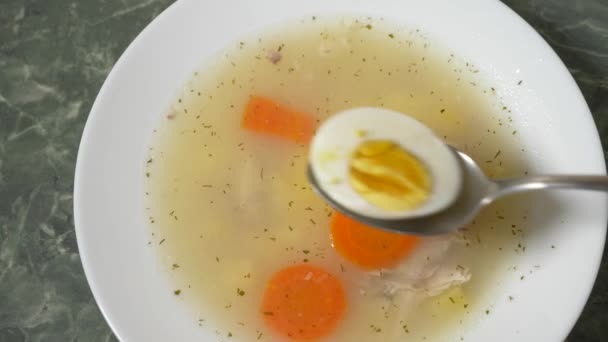 Кто-то ест куриный суп с яйцом из тарелки. 4k, slow motion — стоковое видео