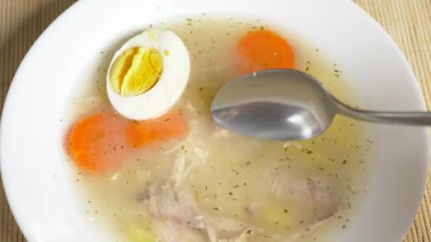 Кто-то ест куриный суп с яйцом из тарелки. 4k, slow motion — стоковое видео