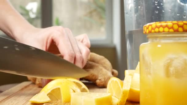 As mãos femininas cortam uma faca com limão para uma bebida feita de frutas cítricas feitas à mão com raiz de gengibre. 4k — Vídeo de Stock