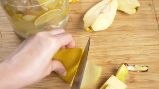 Mains de femmes coupées en morceaux de coing pour une boisson à base d'agrumes faits à la main avec du gingembre. 4k , — Video