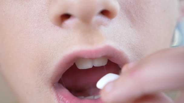 De perto, a boca de uma criança. O rapaz põe a pastilha elástica na boca e mastiga-a. 4k, câmera lenta — Vídeo de Stock
