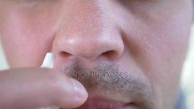 Bir adam su sıçramalarına burun tıpta. burun spreyi, yakın çekim, 4k