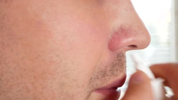Человек брызгает лекарством в нос. спрей для носа, крупный план, 4k — стоковое видео