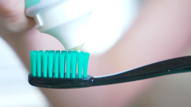 Squeezing toothpaste from a tube onto a toothbrush. Macro, close-up 4k. slow motion, copy space — Stock Video