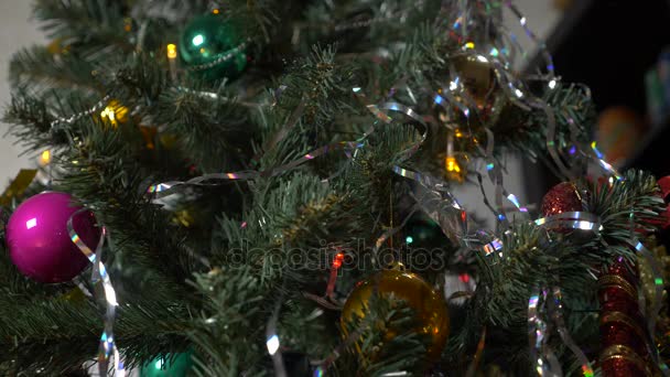 Egy díszített és kivilágított karácsonyfa, a szép csillogó labdát tarka homályos fények, füzér. 4k, lassú mozgás