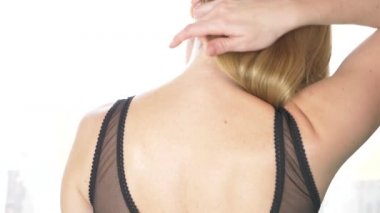 Arkadan Görünüm, yakın çekim, 4 k, ağır çekim. sarışın bir kadın sutyen askısı ile bir omuz kapalı alır.