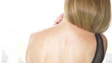 Arkadan Görünüm, yakın çekim, 4 k, ağır çekim. sarışın bir kadın sutyen askısı ile bir omuz kapalı alır.