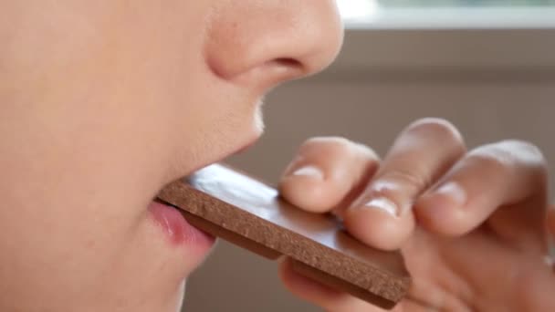 Primer plano. masticando la boca de los chicos. En cámara lenta. 4k. el chico se pone el chocolate en la boca y lo mastica — Vídeos de Stock