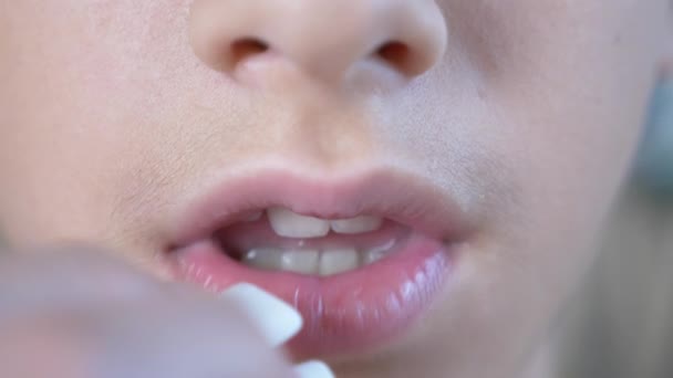 Gros plan, la bouche d'un enfant. le garçon met le chewing-gum dans sa bouche et le mâche. 4k — Video