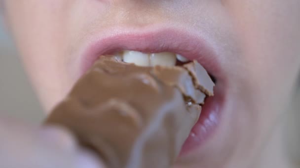 Primer plano. masticando la boca de los chicos. En cámara lenta. 4k. el chico se pone el chocolate en la boca y lo mastica — Vídeos de Stock