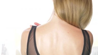 Arkadan Görünüm, yakın çekim, 4 k, ağır çekim. sarışın bir kadın sutyen askısı ile bir omuz kapalı alır.