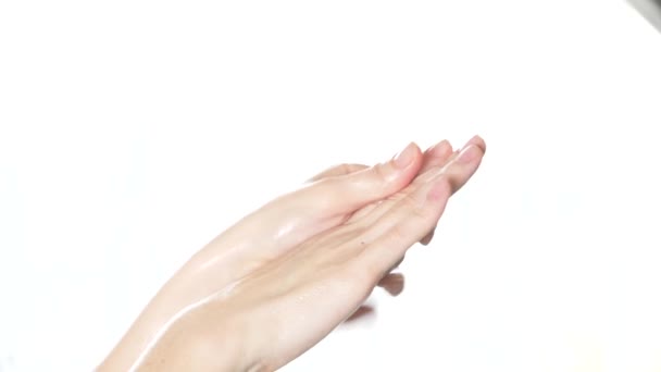 Limpie las manos bien arregladas de una mujer joven aplicando crema de manos, cuidado de la piel sobre un fondo blanco. 4k, cámara lenta, primer plano — Vídeos de Stock