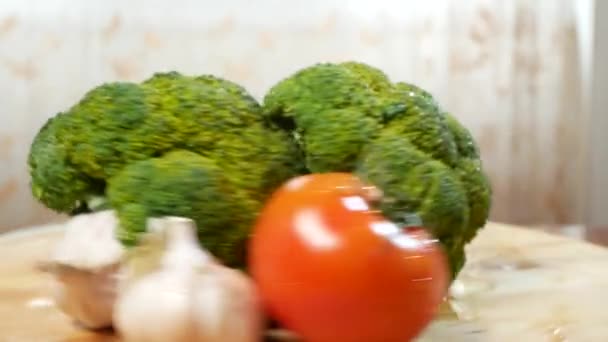 Tomates, brócoli y ajo, girando sobre una tabla de cortar de madera. 4k . — Vídeo de stock