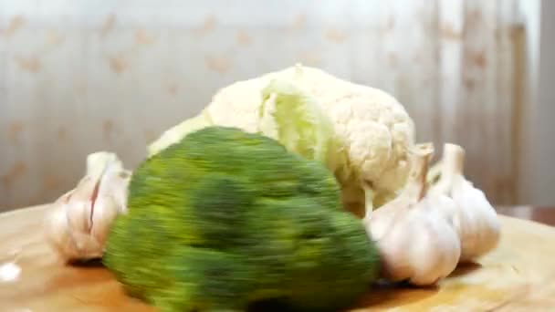 Blomkål, broccoli och vitlök som snurrar på en trä skärbräda. 4k. — Stockvideo