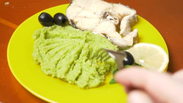 Iemand eet broccoli puree met gestoomde vis. 4k, slow-motion — Stockvideo