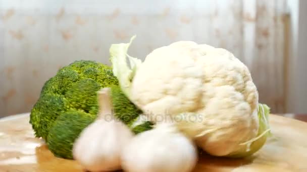 Blomkål, broccoli och vitlök som snurrar på en trä skärbräda. 4k. — Stockvideo