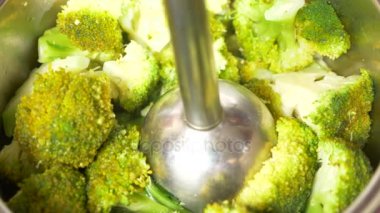 Biri brokoli bir El blender ile püre yapar. yakın çekim, yavaş hareket, 4k. kopya alanı