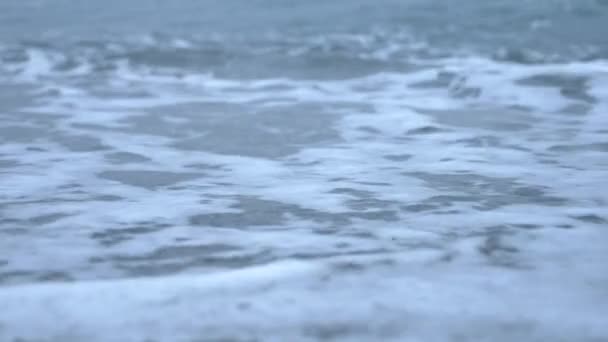 Praia de seixos ao pôr-do-sol. As ondas se espalham e quebram em gotículas. 4k, câmera lenta — Vídeo de Stock