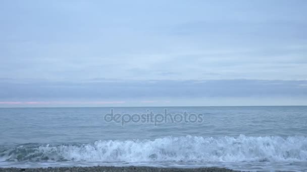 Playa de guijarros al atardecer. Las olas salpican y se rompen en gotitas. 4k, cámara lenta — Vídeos de Stock