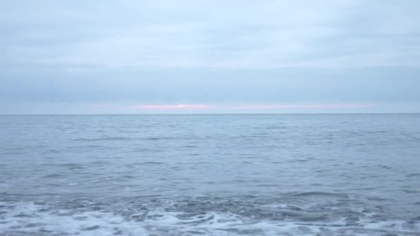 Playa de guijarros al atardecer. Las olas salpican y se rompen en gotitas. 4k, cámara lenta — Vídeos de Stock