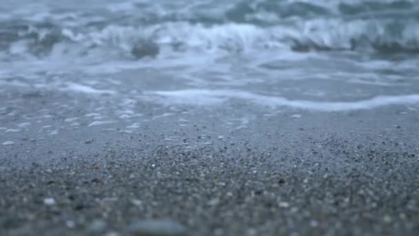 Playa de guijarros al atardecer. Las olas salpican y se rompen en gotitas. 4k, cámara lenta — Vídeo de stock